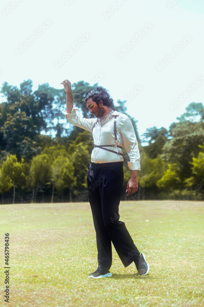 Malaysian Indian man in a field, outdoors, dancing and posing 