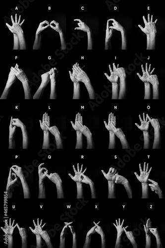 B+W image of hands demonstrating BSL sign language alphabet letters A-Z with text labels isolated against black background