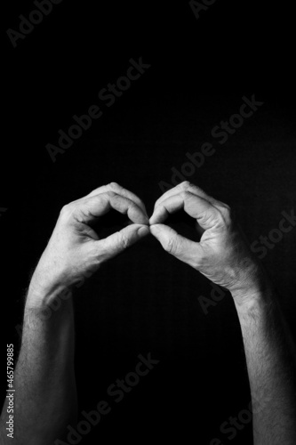 B+W image of hand demonstrating BSL sign language letter B isolated against black background
