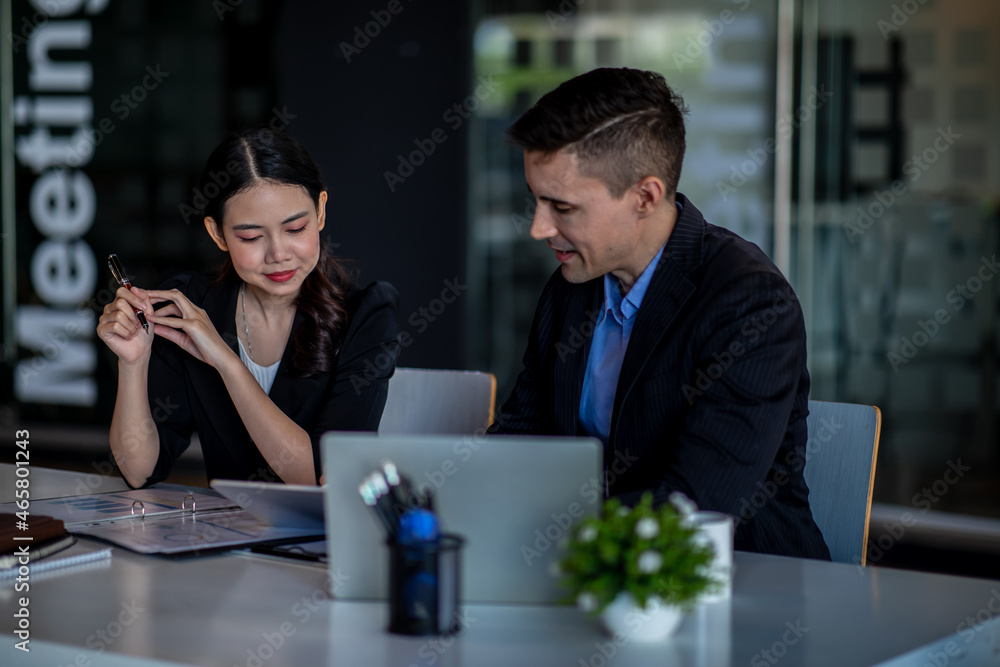 Business people working together. Serious businessman with laptop talking to a businesswoman with papers and tablet. Business partners have a successful meeting in the modern office.