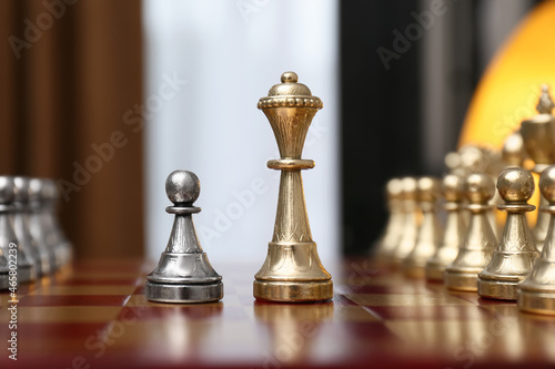 Queen and pawn piece among others on chessboard indoors