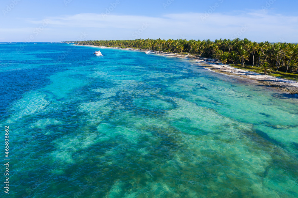 Speed boat floating along tropical island with palm trees near caribbean sea. Dominican Republic. Aerial view Speed boat floating along tropical island with palm trees near caribbean sea. Dominican Republic. Aerial view