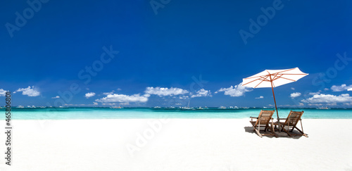Sun umbrellas and wooden beds on tropical beach. Long banner photo