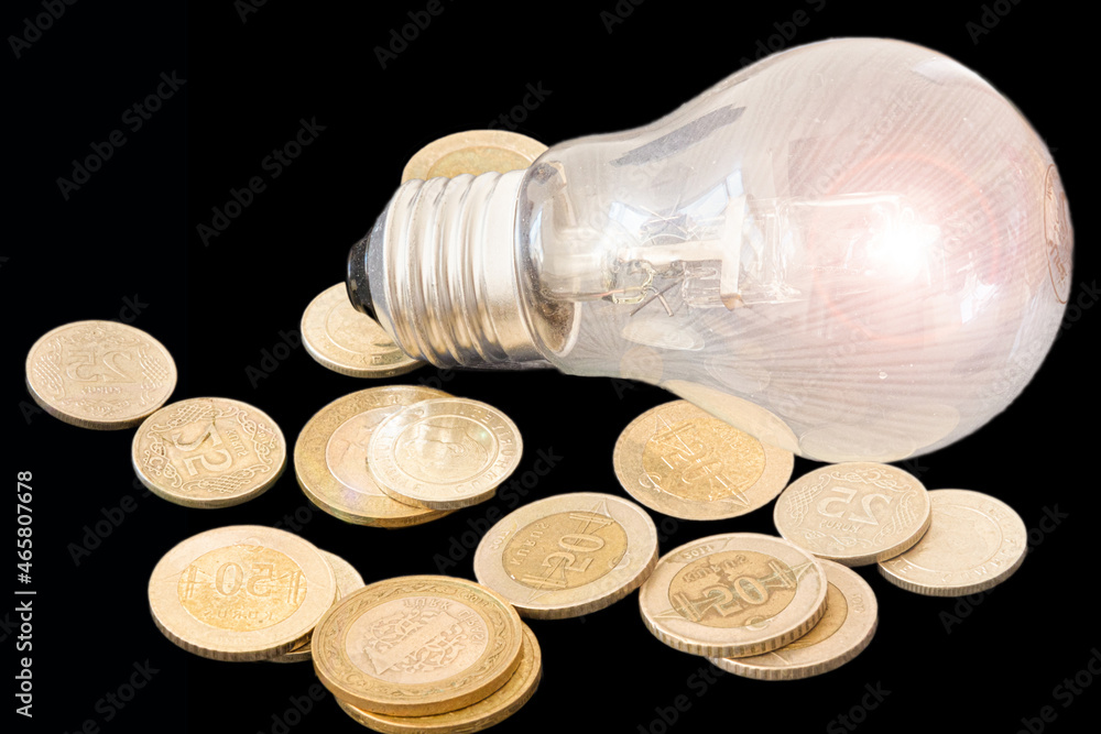 Energy saving light bulb concept idea, glowing light bulb with coins on black background. Energy saving light bulb concept idea, glowing light bulb with coins on black background.