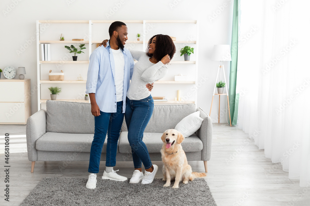 Young black couple hugging at home with dog Young black couple hugging at home with dog