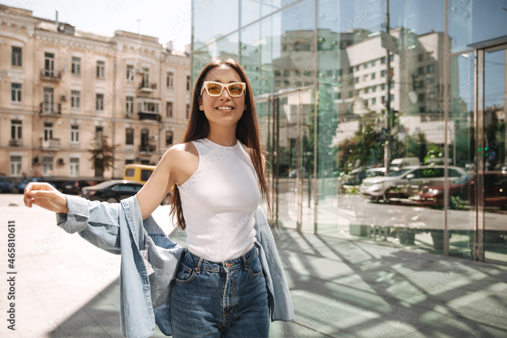 Stylish young asian woman traveling in unfamiliar city having fun. Girl in white T-shirt, shirt and jeans with long dark hair. Concept of enjoying weekend, vacation