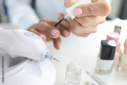 Woman doing her own manicure with pink nail polish closeup