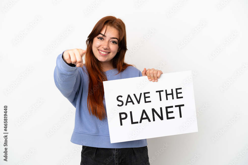 Young redhead woman isolated on white background holding a placard with text Save the Planet and pointing to the front Young redhead woman isolated on white background holding a placard with text Save the Planet and pointing to the front