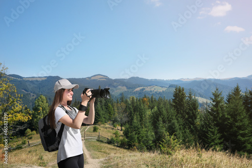 Professional photographer taking picture with modern camera in mountains. Space for text