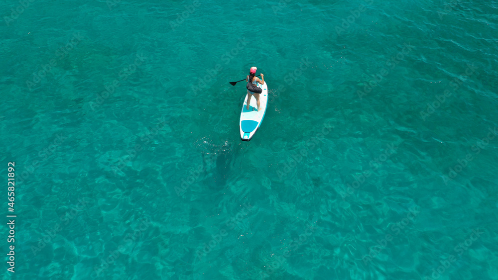 Aerial drone photo of young woman practising paddle board or sup in tropical Caribbean sapphire crystal clear calm waters