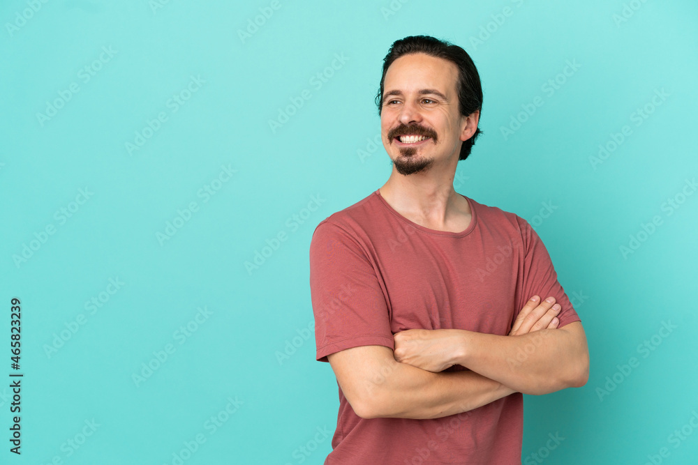 Young caucasian man isolated on blue background with arms crossed and happy Young caucasian man isolated on blue background with arms crossed and happy