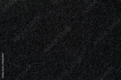 black porous surface of a synthetic sponge for washing dishes and cleaning, close-up. photo with depth of field