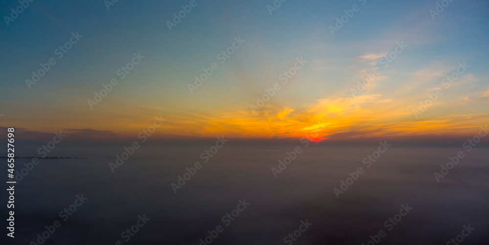 Panorama of sunrise. Blue sky with orange clouds.