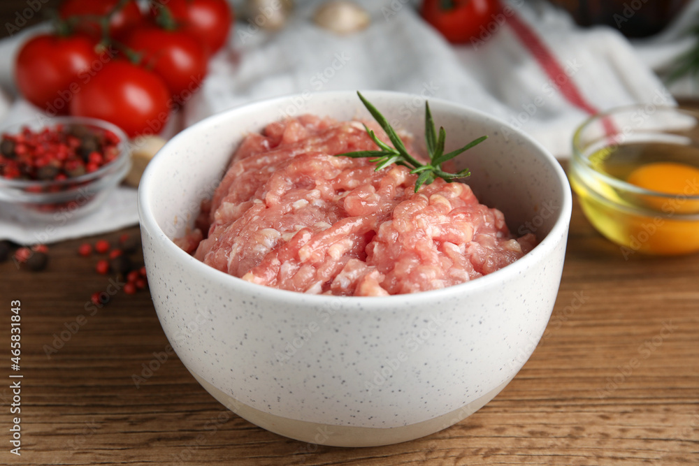 Raw chicken minced meat with rosemary on wooden table, closeup Raw chicken minced meat with rosemary on wooden table, closeup