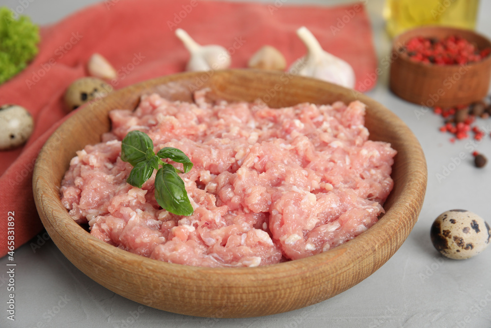 Raw chicken minced meat with basil and quail eggs on grey table, closeup Raw chicken minced meat with basil and quail eggs on grey table, closeup