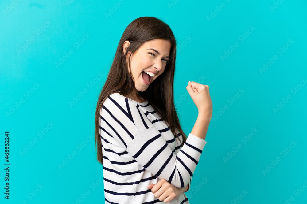 Fototapeta premium Teenager Brazilian girl over isolated blue background celebrating a victory
