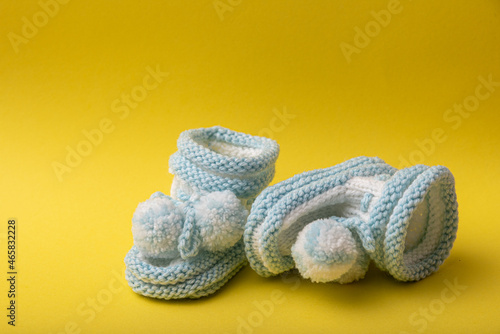 homemade knitted shoes for newborn boys on yellow background