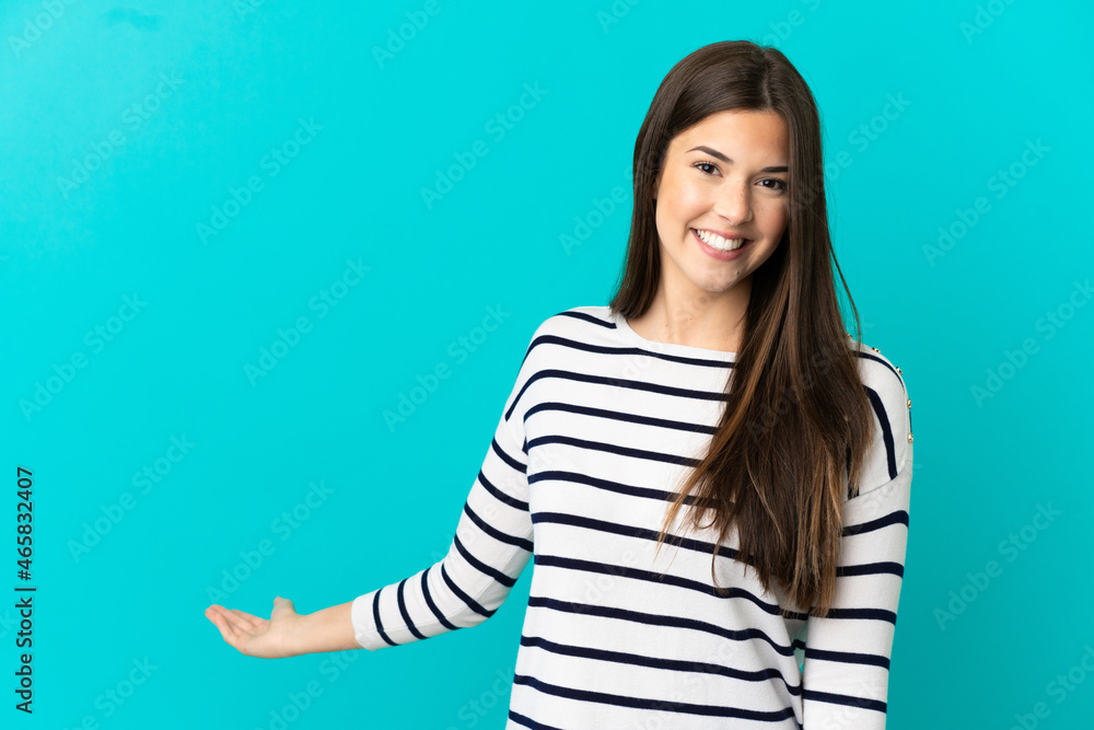 Teenager Brazilian girl over isolated blue background extending hands to the side for inviting to come Teenager Brazilian girl over isolated blue background extending hands to the side for inviting to come