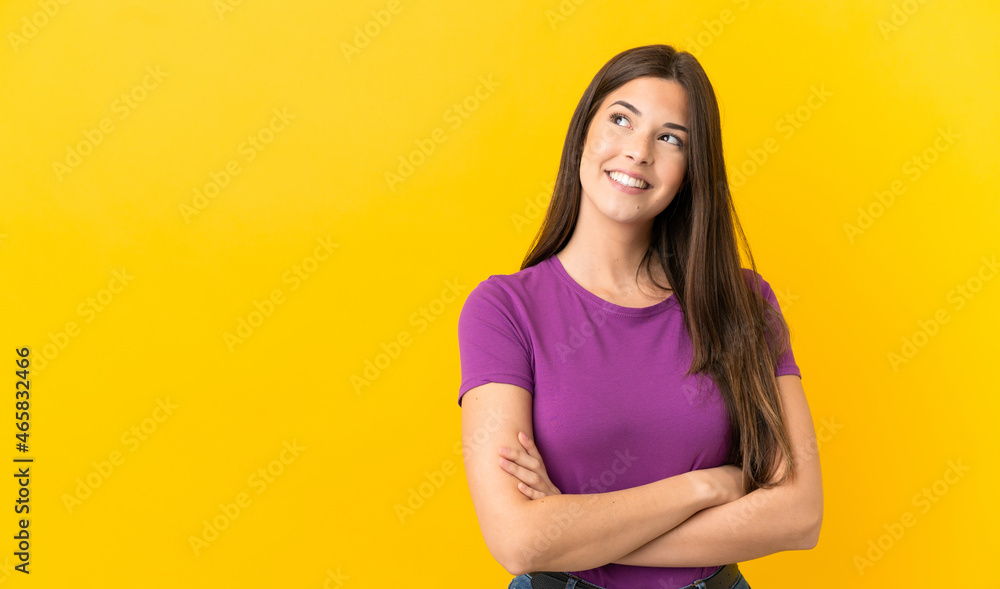 Obraz premium Teenager Brazilian girl over isolated yellow background looking up while smiling