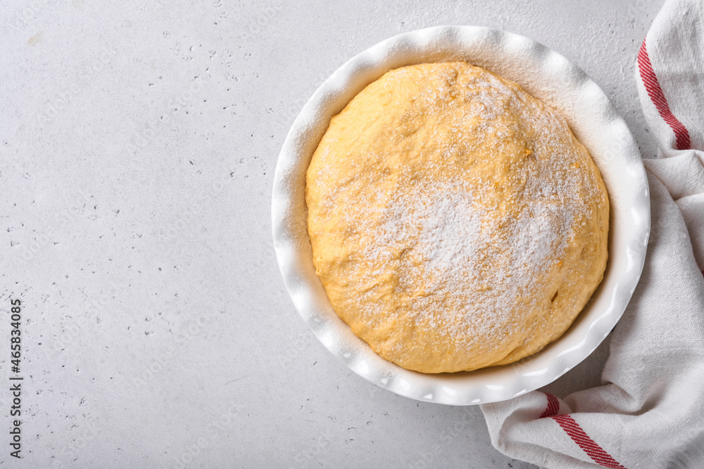 Raw yeast dough with pumpkin in white bowl covered with towel on the floured kitchen table, recipe idea. Concept home baking bread, buns or cinnabon or making dough. Raw yeast dough with pumpkin in white bowl covered with towel on the floured kitchen table, recipe idea. Concept home baking bread, buns or cinnabon or making dough.