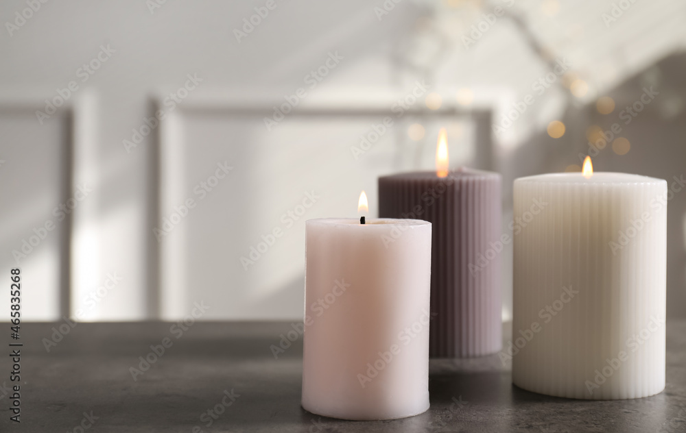 Different burning candles on grey table indoors. Space for text Different burning candles on grey table indoors. Space for text