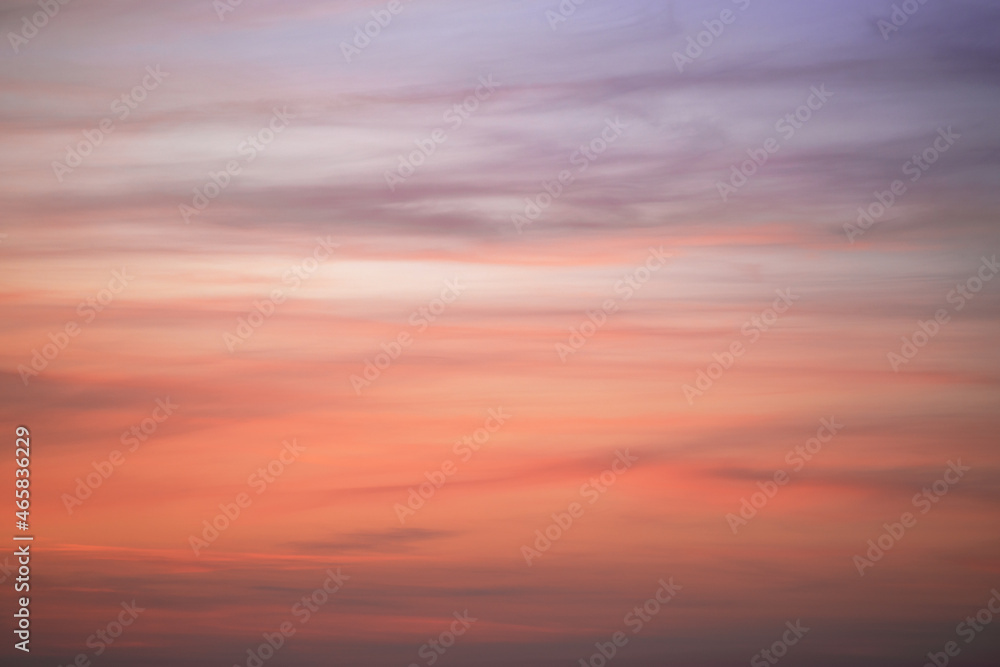 The sky at sunset with feather clouds. The color of the sky changes from purple to dark orange.