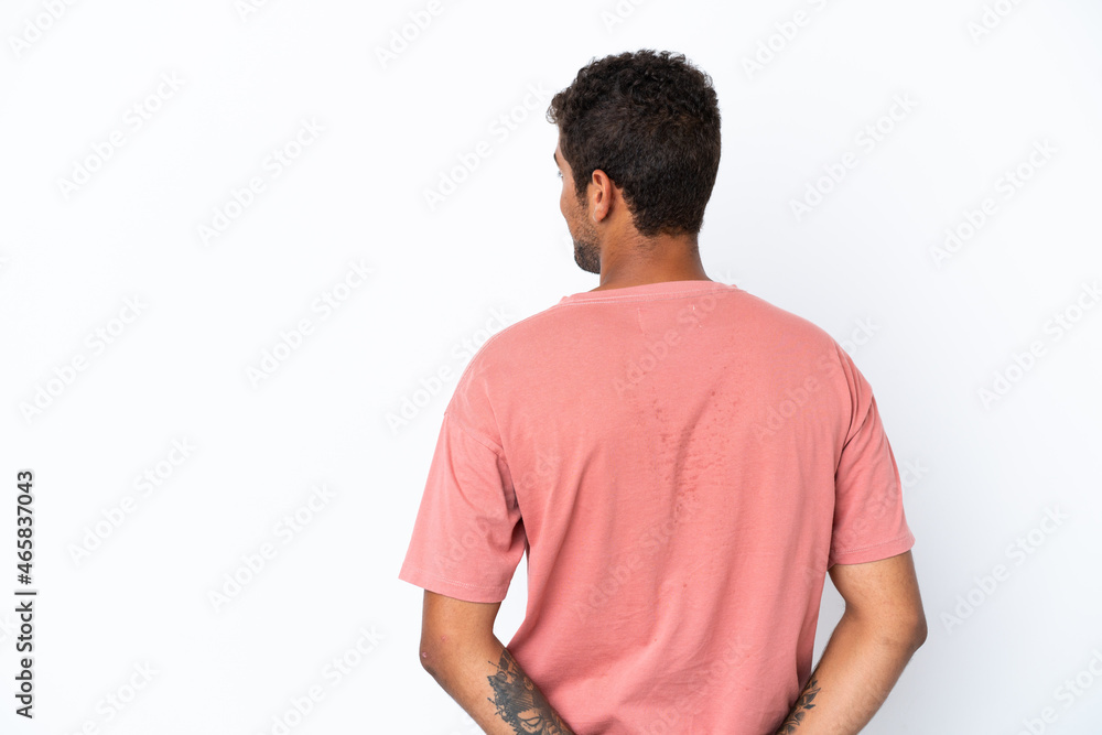 Young handsome Brazilian man isolated on white background in back position and looking back Young handsome Brazilian man isolated on white background in back position and looking back