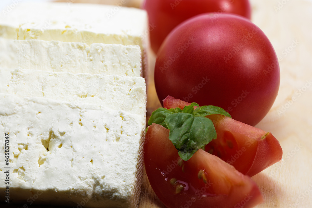 Close up feta cheese, ripe tomatoes, tomato slices, basil Close up feta cheese, ripe tomatoes, tomato slices, basil