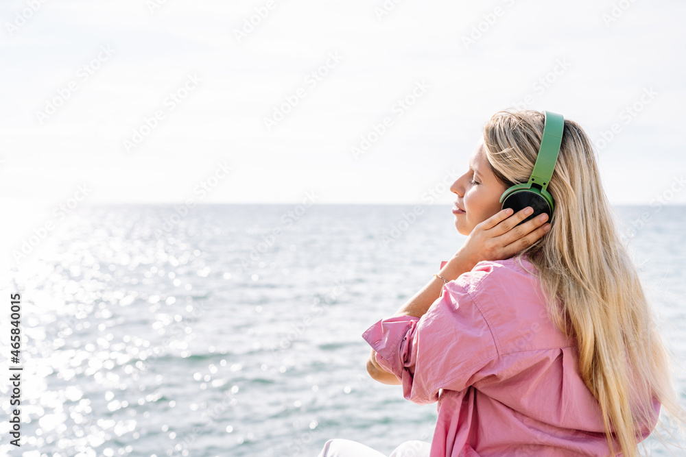 Woman listening to music in headphones on seashore