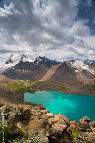 A beautiful alpine lake Ala-Kul in Kyrgyzstan, panoramic view from a height of 3900 m above sea level. A wonderful combination of nature, turquoise water, snowy mountains and clouds.