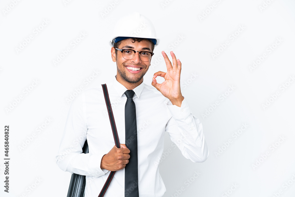 Architect brazilian man with helmet and holding blueprints showing ok sign with fingers Architect brazilian man with helmet and holding blueprints showing ok sign with fingers