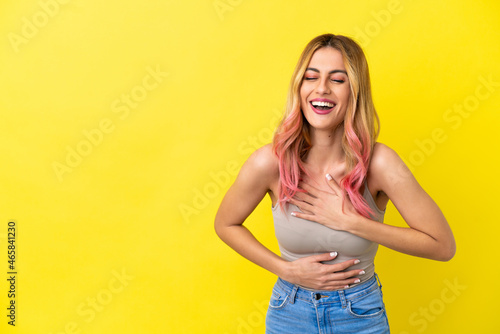 Young woman over isolated yellow background smiling a lot