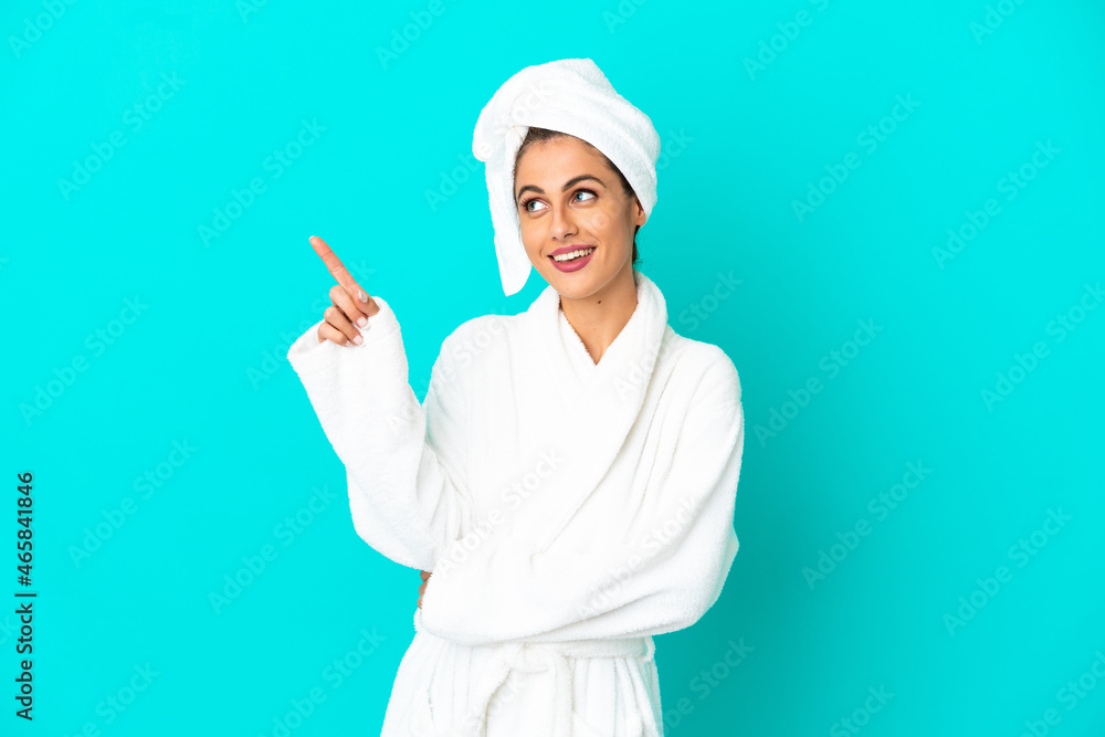 Young woman in a bathrobe over isolated blue background pointing up a great idea Young woman in a bathrobe over isolated blue background pointing up a great idea