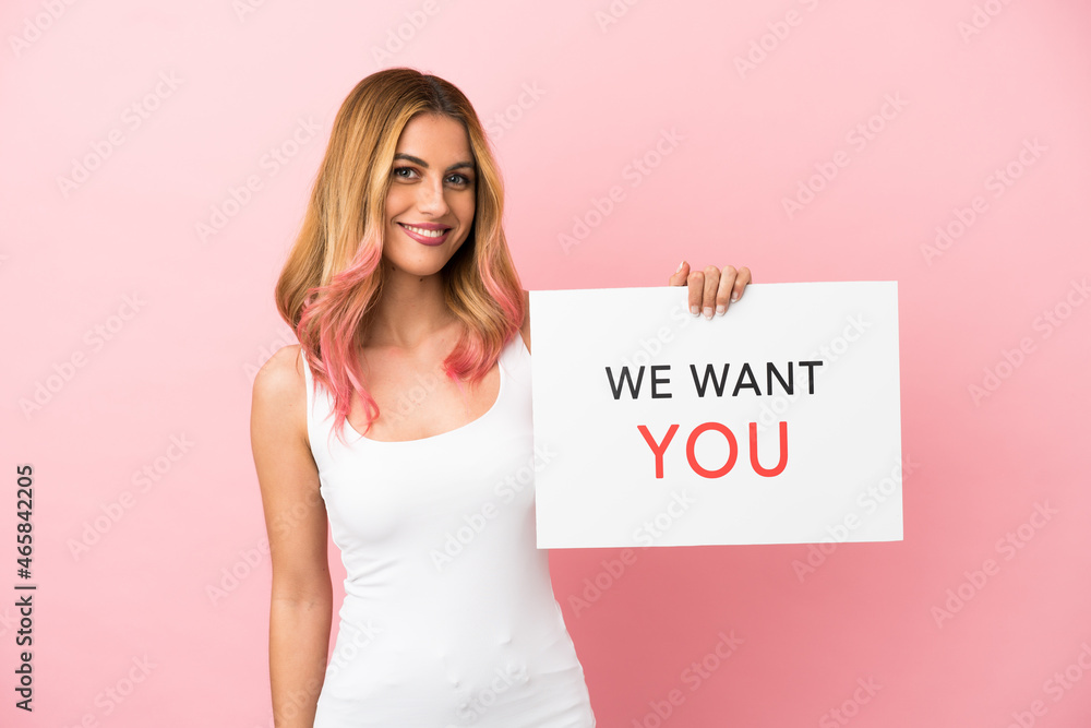 Young woman over isolated pink background holding We Want You board with happy expression Young woman over isolated pink background holding We Want You board with happy expression