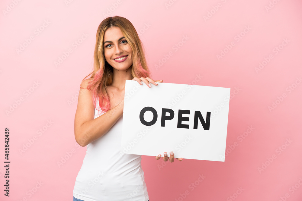 Young woman over isolated pink background holding a placard with peace symbol with happy expression Young woman over isolated pink background holding a placard with peace symbol with happy expression