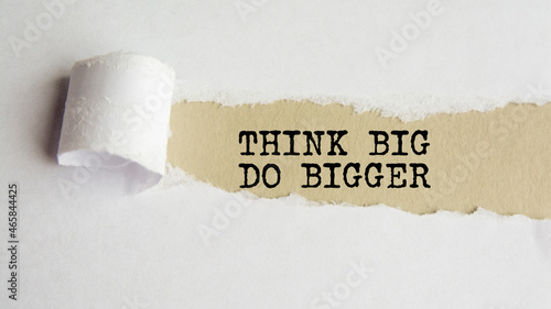 think big do bigger. words. text on grey paper on torn paper background