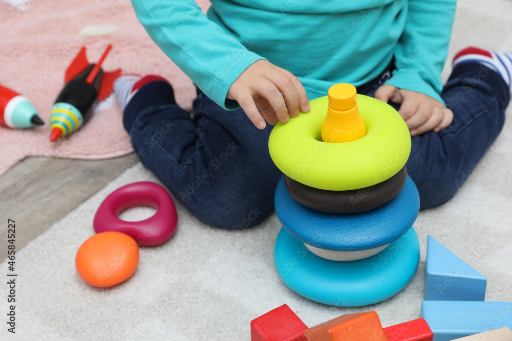 Little child playing with stacking toy on carpet, closeup Little child playing with stacking toy on carpet, closeup