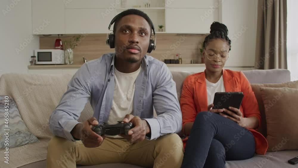 A young adult couple having a confrontation about gaming in their apartment home A young adult couple having a confrontation about gaming in their apartment home