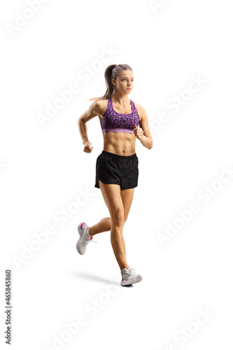 Full length shot of a fit young woman in shorts and crop top jogging