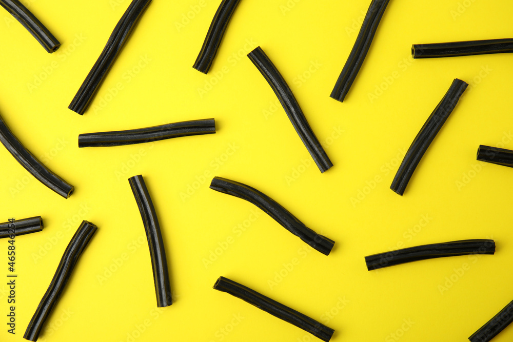 Tasty black liquorice candies on yellow background, flat lay Tasty black liquorice candies on yellow background, flat lay