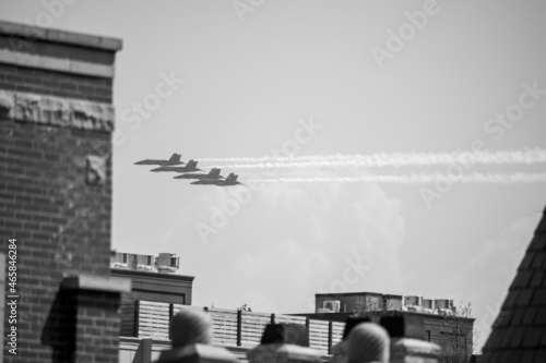 Grayscale shot of a group of people watching an air show during a paradet