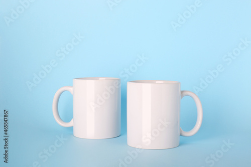 Blank white ceramic mugs on light blue background