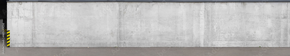 Fototapeta premium a fragment of an urban concrete wall of a building and an asphalt sidewalk, a building facade, a template or source