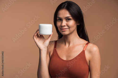 Cute brunette woman with cream jar posing in studio