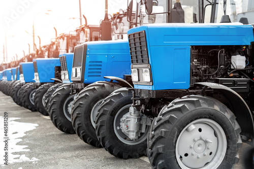 Many different tractors standing in row at agricultural fair for sale outdoors.Equipment for agriculture.Heavy industrial machines presented to agricultural exhibition. Agribusiness leasing concept photo