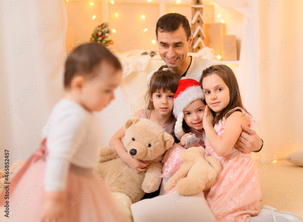 celebrating the new year or Christmas - family portrait of a father and children in home interior decorated with lights celebrating the new year or Christmas - family portrait of a father and children in home interior decorated with lights