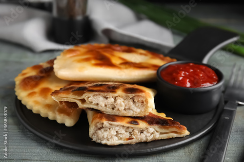 Delicious fried chebureki with ketchup on blue wooden table