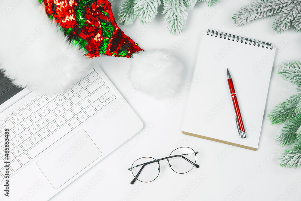 Christmas background, notebook, notepad, pen, santa hat, glasses on a light background. Christmas background, notebook, notepad, pen, santa hat, glasses on a light background.