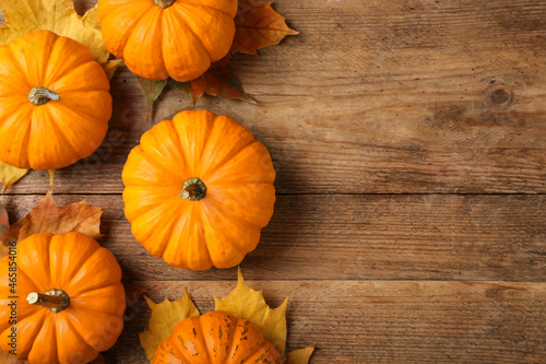 Fresh ripe pumpkins and dry leaves on wooden table, flat lay. Space for text