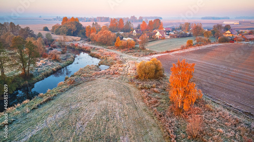 Obraz na płótnie Autumn rural landscape. Frost on grass. River, field, meadow, village, fall color trees. w salonie